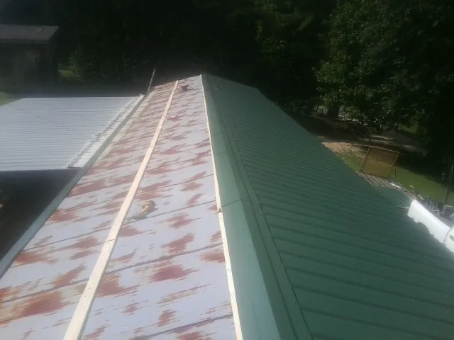 Old rusted panels beside newly installed green metal roofing — Wind Damage Roof Repair by Roofing Brothers in Gouldsboro