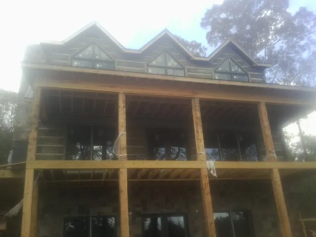 Dormers and porch framing on a large log home under construction — Roof Coating work by our crew in Gouldsboro