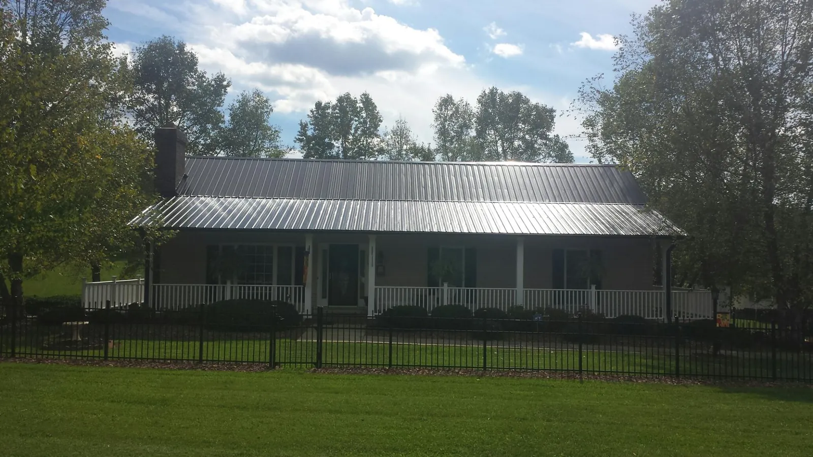 Gray metal roof on a brick ranch with a full width front porch — Gutter Guard Installation work by our crew in Gouldsboro