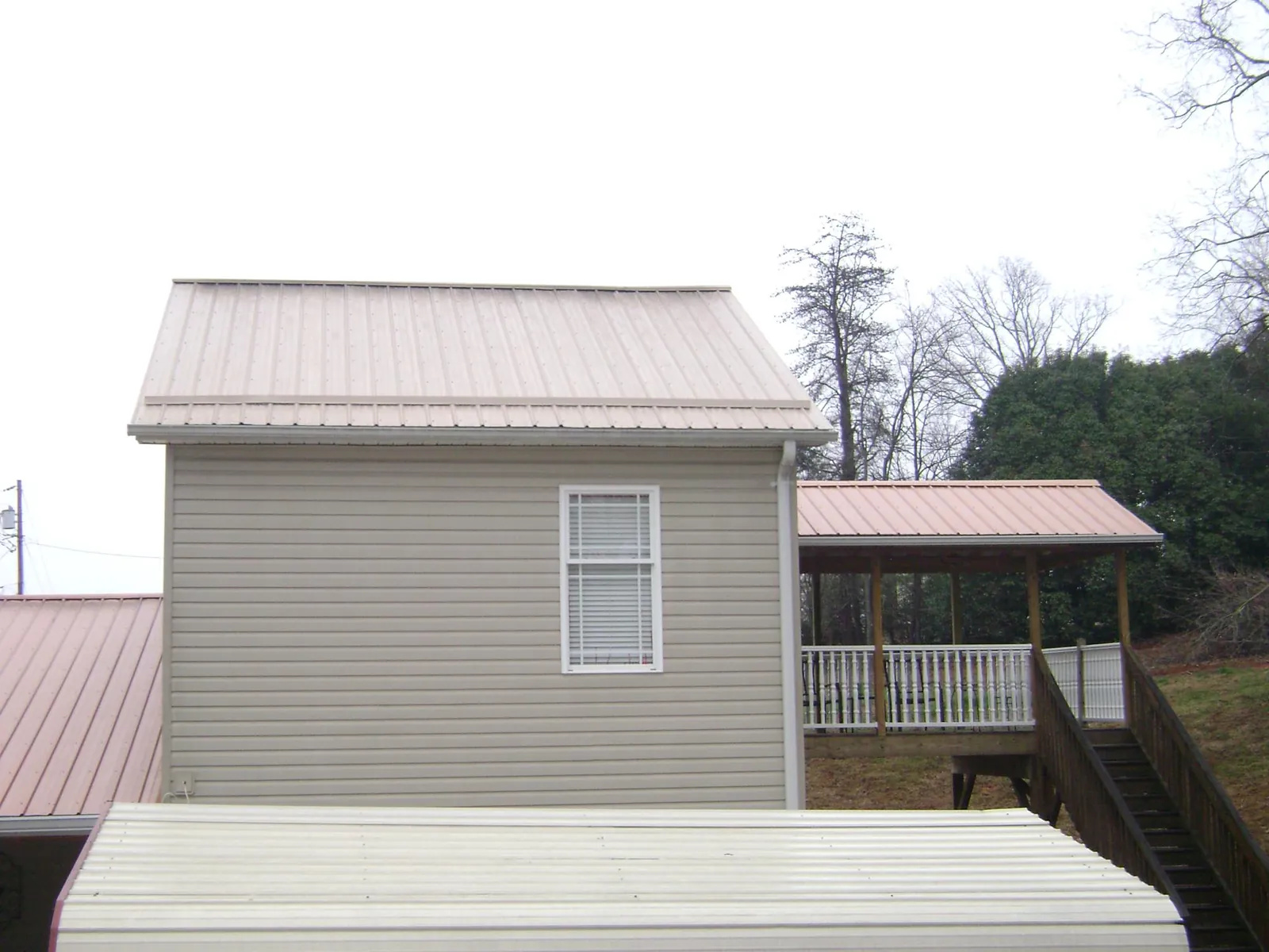 Tan metal roofs on a two story addition and attached porch, from a Roof Replacement job in Gouldsboro