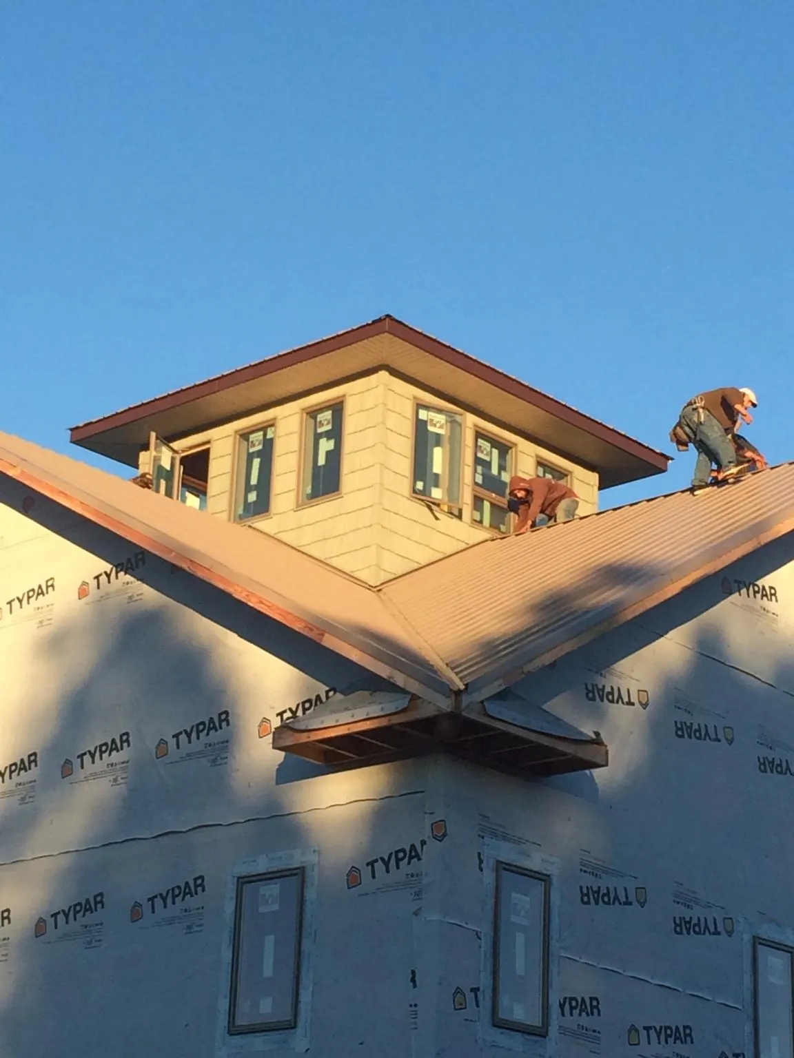 Roofers working around a rooftop cupola on a new metal roof at sunset — Roof Waterproofing in Gouldsboro by Roofing Brothers